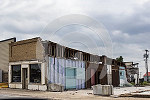 Old storefront in American small town showing walls where another building has been demolished with interior walls visible - very