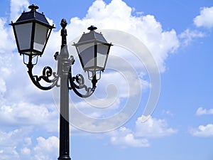 Old street decorated lamppost against cloudy blue sky