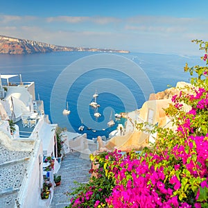 Old street with flowers, traditional Greek houses and a staircase to the sea, Santorini, Greece