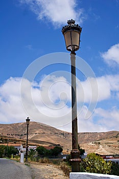 Old street lamp against the blue sky with mountains on the background, Betancuria, Fuerteventura