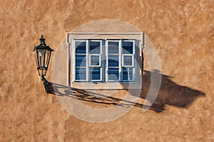An old street lamp and shadow on a wall with a window