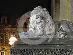 Old street light and lion sculpture on the 19th century leeds city hall building at night with old city building in the background