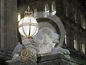 Old street light and lion sculpture on the 19th century leeds city hall building at night with the historic library building in