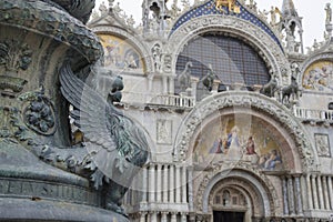 Old street ornament with winged lions and San Marco Basilica in the background, in St. Mark Square, famous tourist attraction in