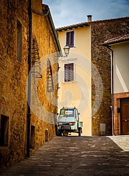 Old street in San quirico d`orcia Italy with old piaggio car