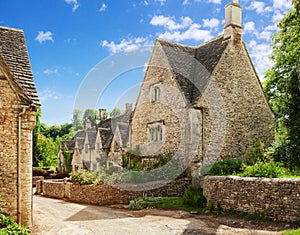 Old street with traditional Cotswold cottages in a sunny spring morning, Bibury, Gloucestershire, England, UK
