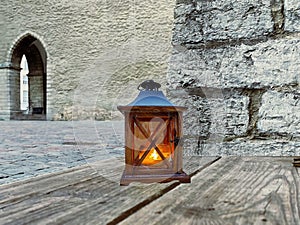 Old street  wooden lantern yellow light on wooden bench near  medieval wall in  old town of Tallinn