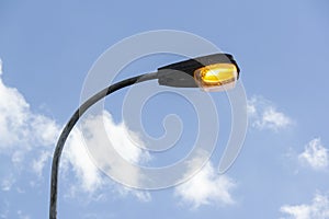 Old streetlamp shining in the afternoon sky with sodium-vapor lamp