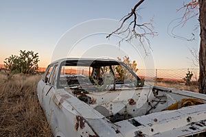 An old stripped white car at the back of the police station of the ghost town called Putsonderwater in South Africa