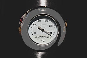 Old style analog thermometer on the metal background. high temperature concept