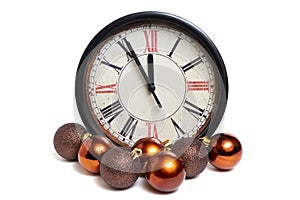 Old style classic clock with roman numbers showing almost twelve o` clock and some colorful christmas balls isolated on white bac