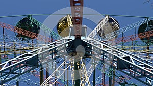 Old-style colorful Ferris wheel rotating on the blue sky background