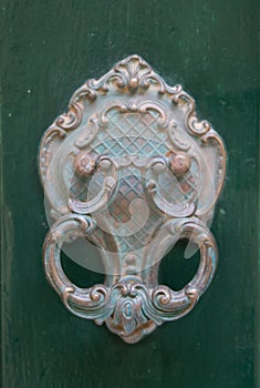 An old style decorative bronze door handle on a wooden green door, the distinctive feature and symbol of Malta in Mdina.