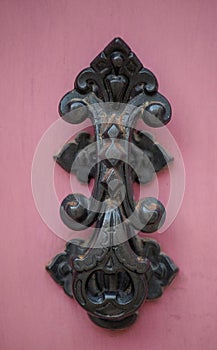 An old style decorative bronze door handle on a wooden red door, the distinctive feature and symbol of Malta in Mdina.