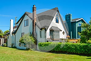 Old style family house with lawn and hedgerow in front on blue sky background