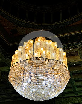 Old Style huge lantern hanging in the dome of Islamic architechture with golden shining lights and dark backdrop photo