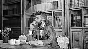 Old style and male fashion. Bearded man sits in library with old book. Mature man in smart suit thinks. Professor with