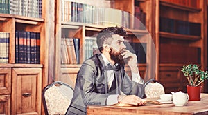 Old style and male fashion. Bearded man sits in library with old book. Mature man in smart suit thinks. Professor with