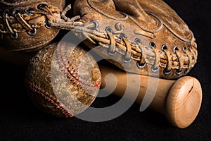 Old style mitt, badly stained and scratched baseball, and brand new shiny bat