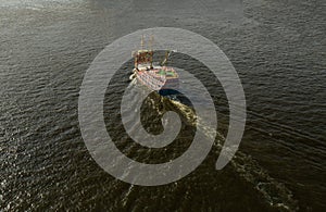 Old style pirate ship motoring without sails in open water towards sun