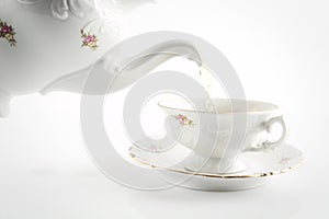Old-style pouring tea to cup on white background