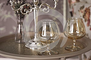 Old style retro candles and wine glass on a tray, vintage home decor on an a table, light tones