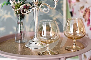 Old style retro candles and wine glass on a tray, vintage home decor on an a table, light tones