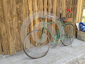 Old style rusty green bicycle and wooden wall