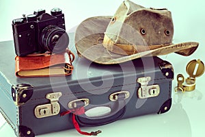 Old-style suitcase, camera, travel hat, notebook, map, retro style compass. The concept of preparing for an adventure around the