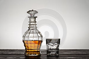 Old style vintage whiskey decanter and a glass on wooden table