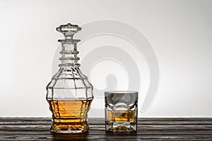 Old style vintage whiskey decanter and a glass on wooden table