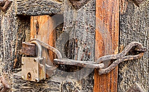 Old styled rusty chain door lock on the wooden door