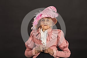 Old stylish lady in mauve jacket and a hat