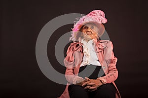 Old stylish lady in mauve jacket and a hat photo