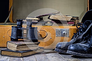 Old stylish suitcase. Military muddy shoes on a suitcase. Suitcase on a wooden table.