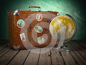 Old suitcase with globe on wood background. Travel or tourism c
