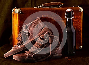 Old suitcase, sneakers, bottle wine, coins. Vintage style photo