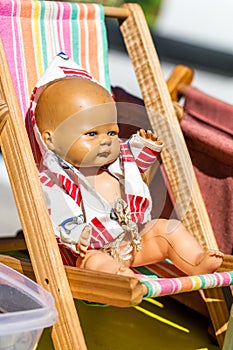 Old summer doll on a small deckchair at street fair