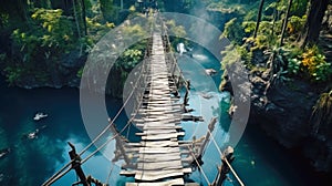 Old suspension bridge across river in jungle, perspective view of hanging vintage wooden footbridge. Scenery of tropical forest