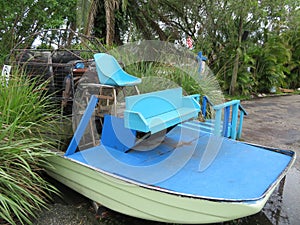 Old swamp buggy airboat docked on land in tropical area