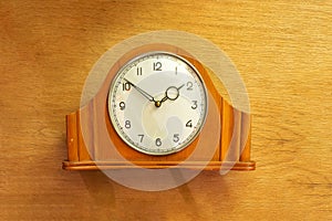 Old table clock made of wood. Mechanical. On a wooden background
