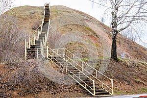 An old tall wooden staircase rises on a large mountain. The ladder symbolizes growth, ascension, aspiration, willpower. Tetyushi,