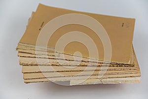 An old tattered book against a neutral background. Brown pages. Softcover. Torn text blocks. Selective focus