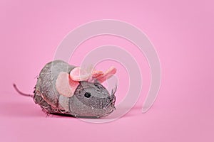 Old tattered cat toy mouse with threads sticking out  on pink background