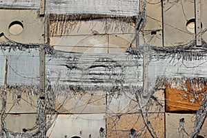 Old tattered insulation panels, torn nylon burlap sacks and wooden plamks on a wall of abandoned building