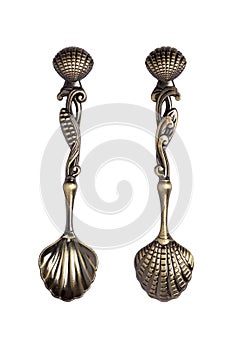 An old tea spoon with a rich decorated handle in the shape of a sea shell. Marine theme. On a white background.