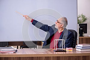 Old teacher physicist sitting in the classroom