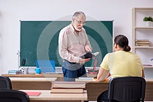 Old teacher and young male student in the classroom