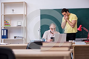 Old teacher and young male student in the classroom