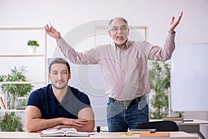 Old teacher and young male student in the classroom